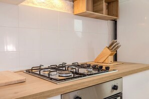 A kitchen with a gas stove, wooden countertop, and a knife block. - Appartamento delle Margherite by Wonderful Italy (Budoni)