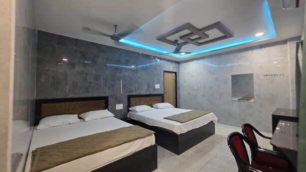 Een hotelkamer met twee bedden, een plafondventilator en een kleine tafel met stoelen.