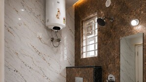 Een badkamer met toilet, bidet en wastafel, marmeren wanden en een boiler.