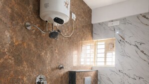 Een badkamer met een marmeren wand, een ingebouwd toilet en een douchegedeelte.