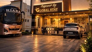Een hotel met een bord waarop 'Global Stay' staat en een bus die ervoor geparkeerd staat.