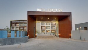 Une entrée d’hôtel moderne, avec une enseigne indiquant « HÔTEL DESERT INN ».