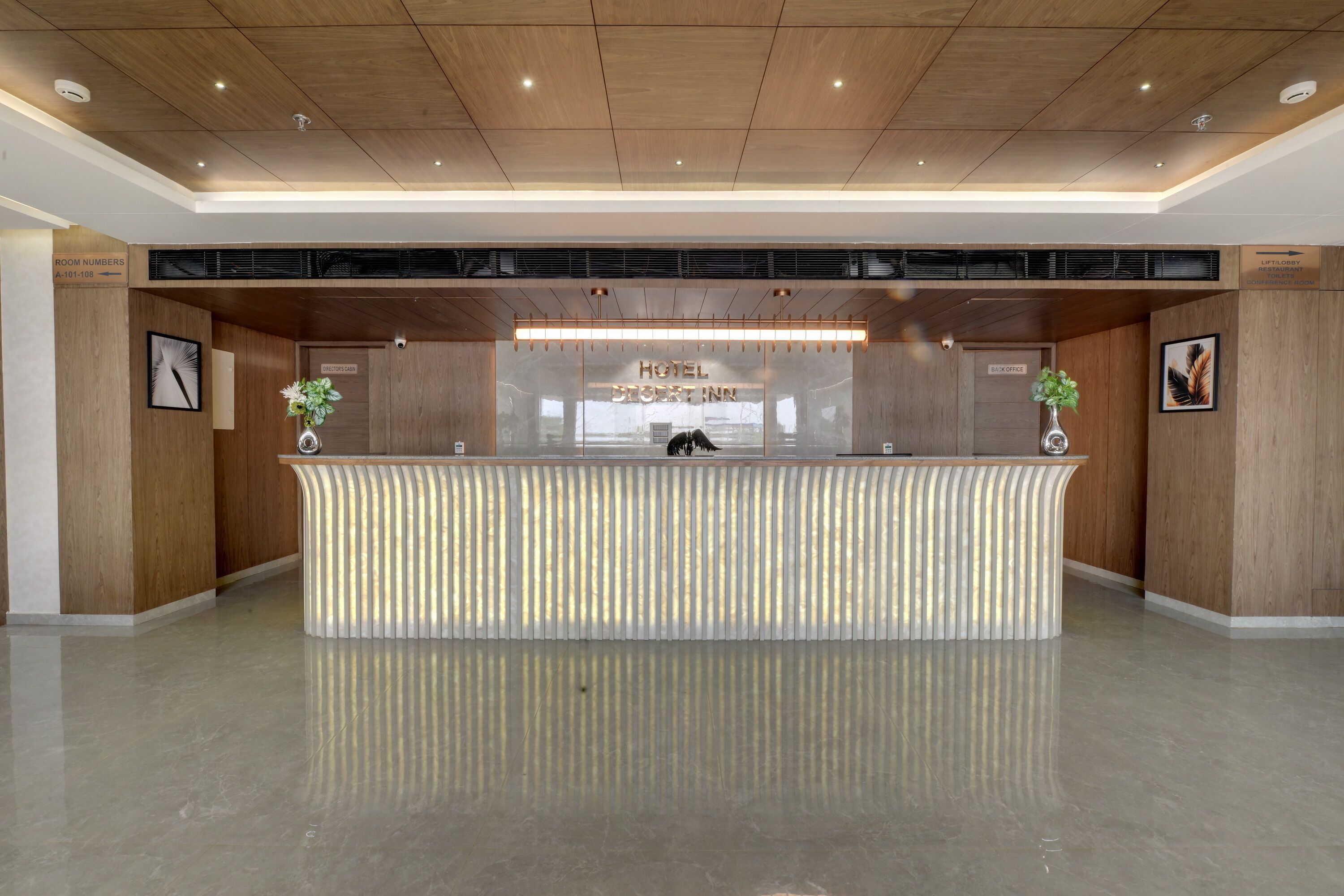 A hotel reception desk with a modern design, a sign indicating the hotel's name, and directional signs for various hotel facilities.
