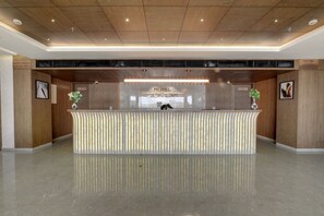 A hotel reception desk with a modern design, a sign indicating the hotel's name, and directional signs for various hotel facilities.