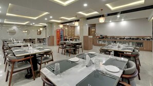 A modern dining area with multiple tables, chairs, and a buffet setup. - Desert Inn Beacon Greater Rann of Kutch (Bhuj)