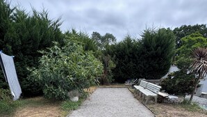 A gravel pathway leading through a garden with benches and potted plants. - A traditional Landes-style house nestled between the ocean, the forests, and the lakes (Ondres)
