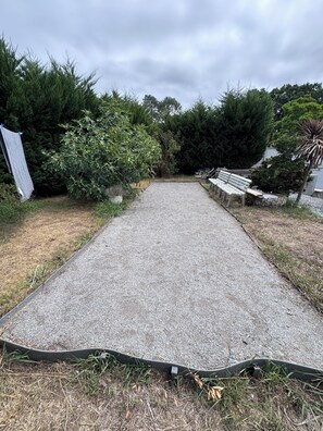 Ein Kiesweg führt durch einen Garten mit Bänken und Kübelpflanzen.