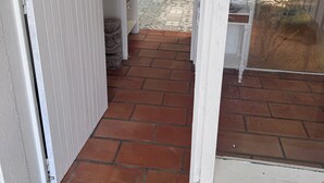 A corridor with a tiled floor leading to a room with a bed and a window. - A traditional Landes-style house nestled between the ocean, the forests, and the lakes (Ondres)