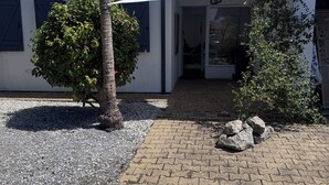 A building with a tiled roof, a gravel pathway, and a white awning. - A traditional Landes-style house nestled between the ocean, the forests, and the lakes (Ondres)
