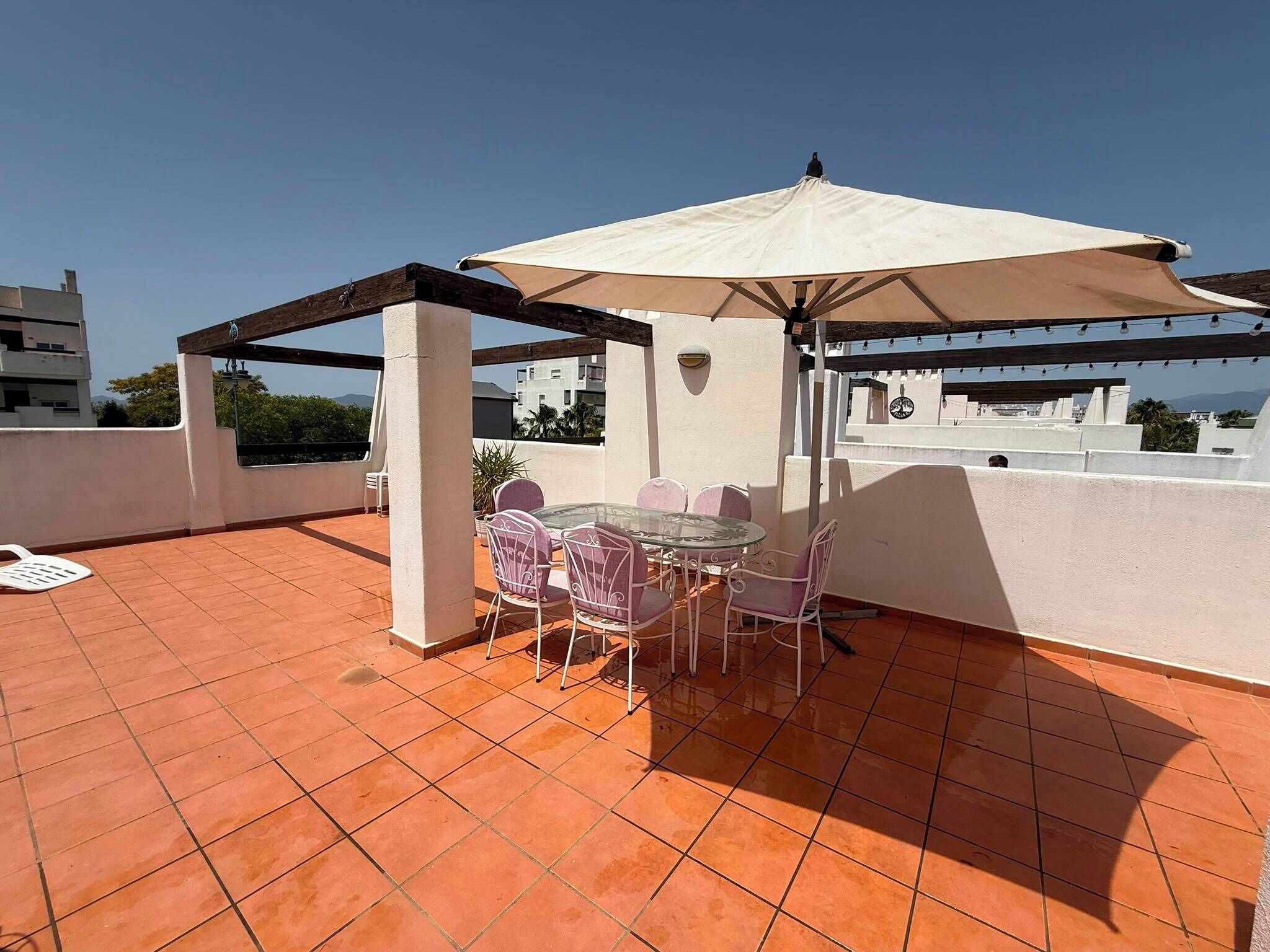 Een terras met een tafel en stoelen, een pergola en uitzicht op de stad.