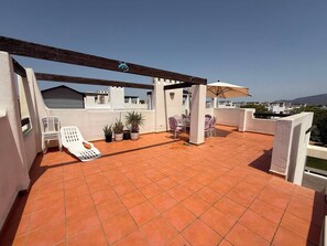 A rooftop terrace with terracotta tiles, white lounge chairs, potted plants, and a pergola. - Alhama County - Apartment 186 N3 (MC)