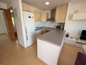A modern kitchen with a refrigerator, microwave, sink, and a built-in oven. - Alhama County - Apartment 186 N3 (MC)
