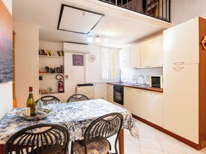 A compact kitchen with a dining area, featuring a microwave, oven, and a small window. - Apartment Lily by Interhome (Imperia)
