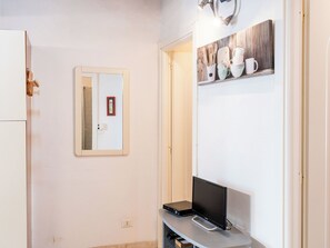 A small kitchenette with a refrigerator, a mirror, and a shelf with kitchenware. - Apartment Lily by Interhome (Imperia)