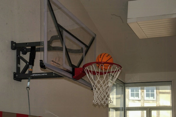 A basketball hoop with a net, attached to a wall with a metal frame.