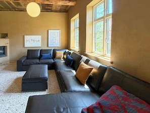 A modern living room with a sectional sofa, a fireplace, and artwork on the walls.