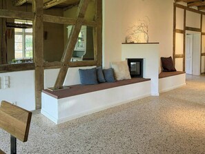A room with a built-in bench, a fireplace, and a large window.