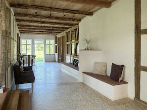 A spacious room with a high ceiling, a built-in bench, and a view through large windows.