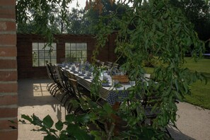 An outdoor dining area with a brick wall, a large window, and a table set for four.