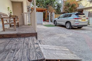 A wooden deck leading to a house with a parked car and a mailbox.