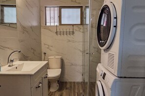A compact bathroom with a sink, toilet, and a washing machine. - Free Parking · Private Studio with Terrace (Herzliya)