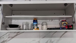 Ein Küchenschrank mit Regalen, der verschiedene Gegenstände wie eine Dose, ein Glas, ein Messbecher und Gläser enthält.
