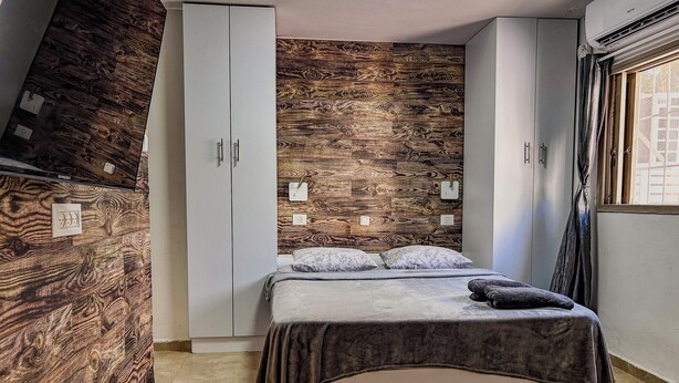 Ein Schlafzimmer mit einem Bett, einem Kleiderschrank und einer Wand mit Holzoptik.