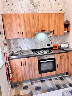 Una cuina moderna amb armaris de fusta, forns a gas i forn integrat.