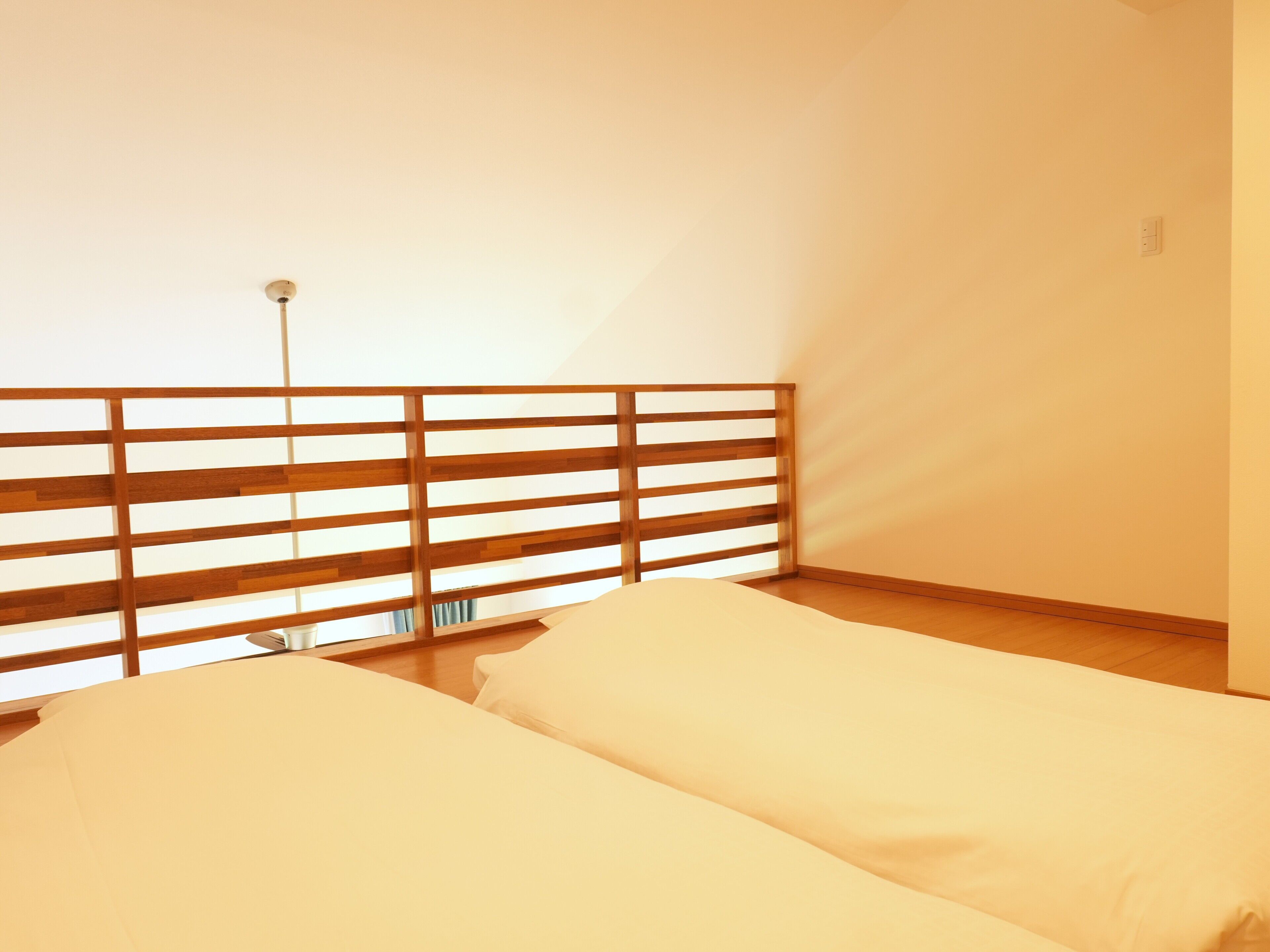 A room with two beds, a wooden headboard, and a single light fixture.
