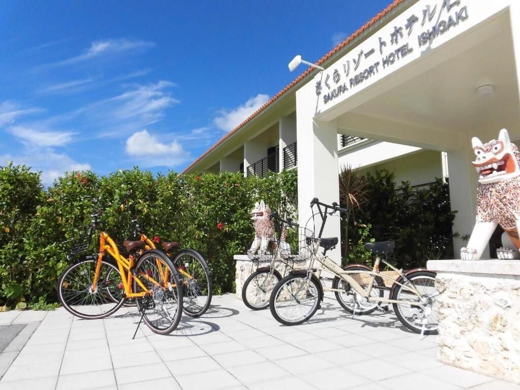 A hotel entrance with a sign, a statue, and bicycles parked in front.