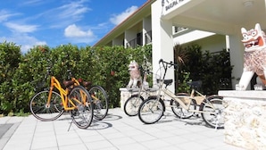 A hotel entrance with a sign, a statue, and bicycles parked in front. - SAKURA RESORT HOTEL ISHIGAKI (Ishigaki)
