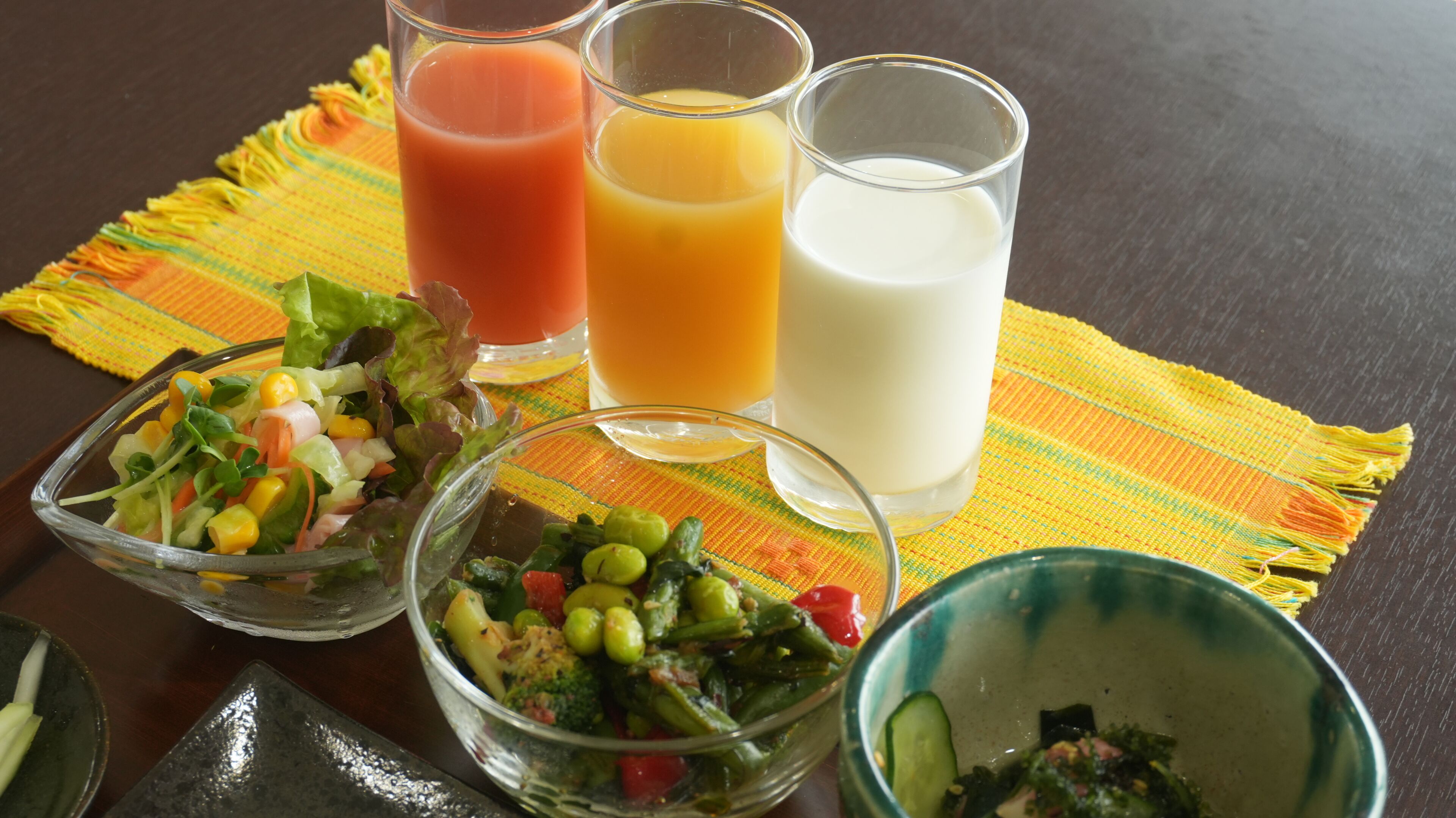 Una mesa con tres vasos de jugo y dos ensaladeras.