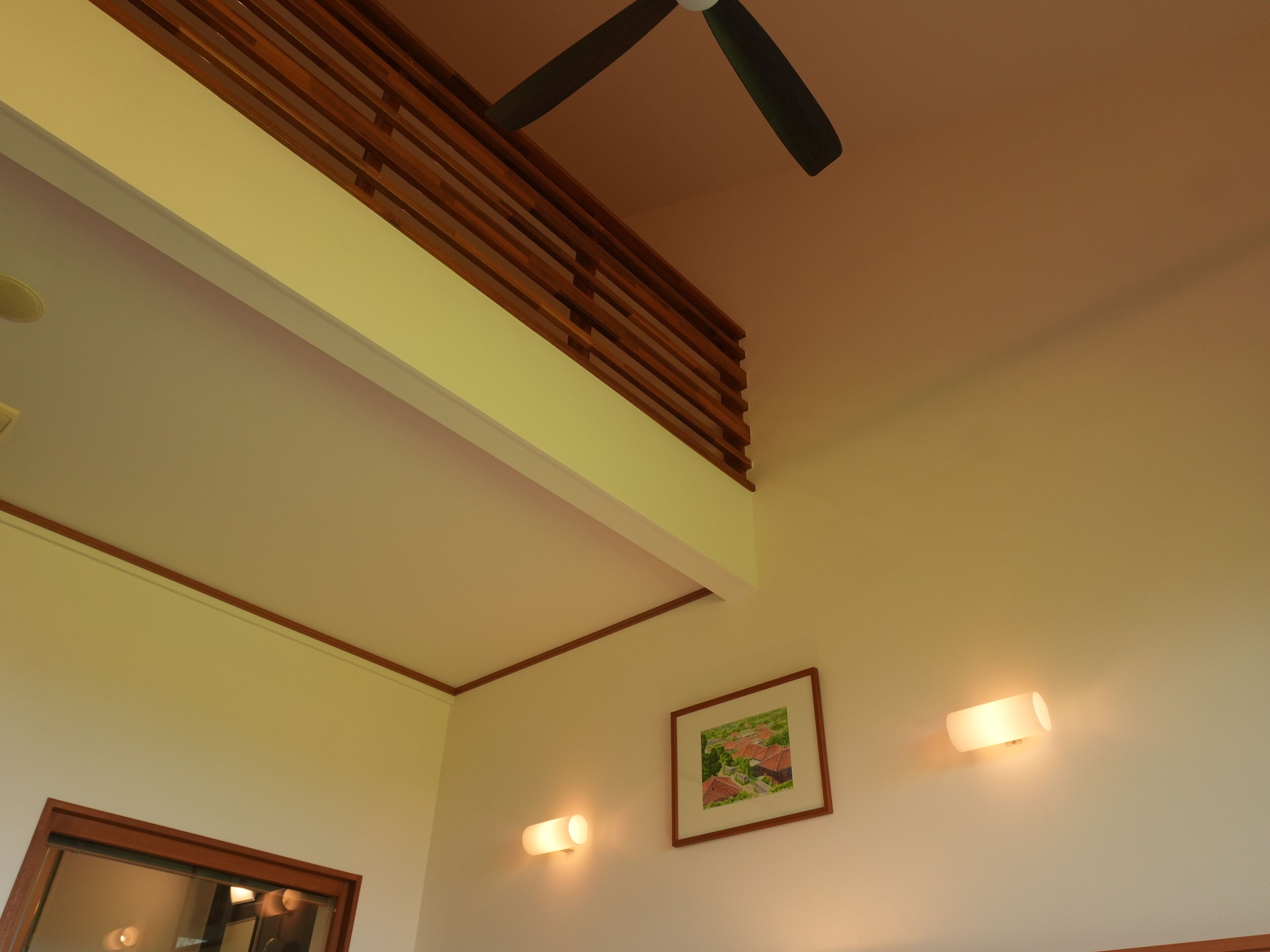 A room with a sloped ceiling, a ceiling fan, and a framed picture on the wall.