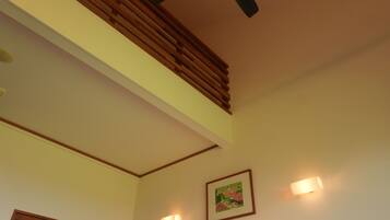 A room with a sloped ceiling, a ceiling fan, and a framed picture on the wall.