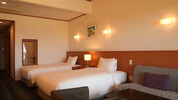 A hotel room with two beds, a sofa, a table, and a mirror.