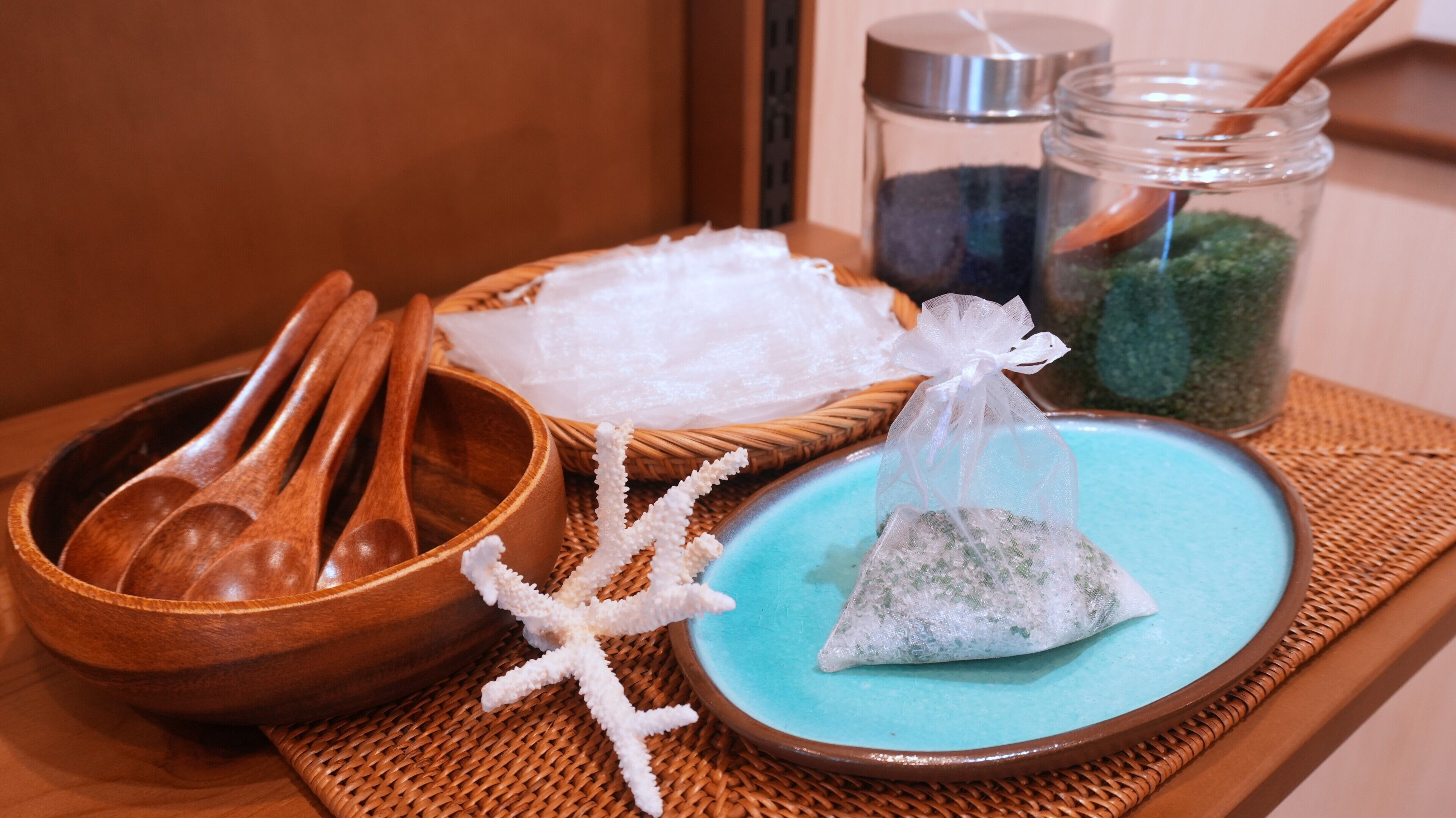 A tray with a wooden bowl, a blue plate with a tea bag, a starfish decoration, and a small basket of white cloth.