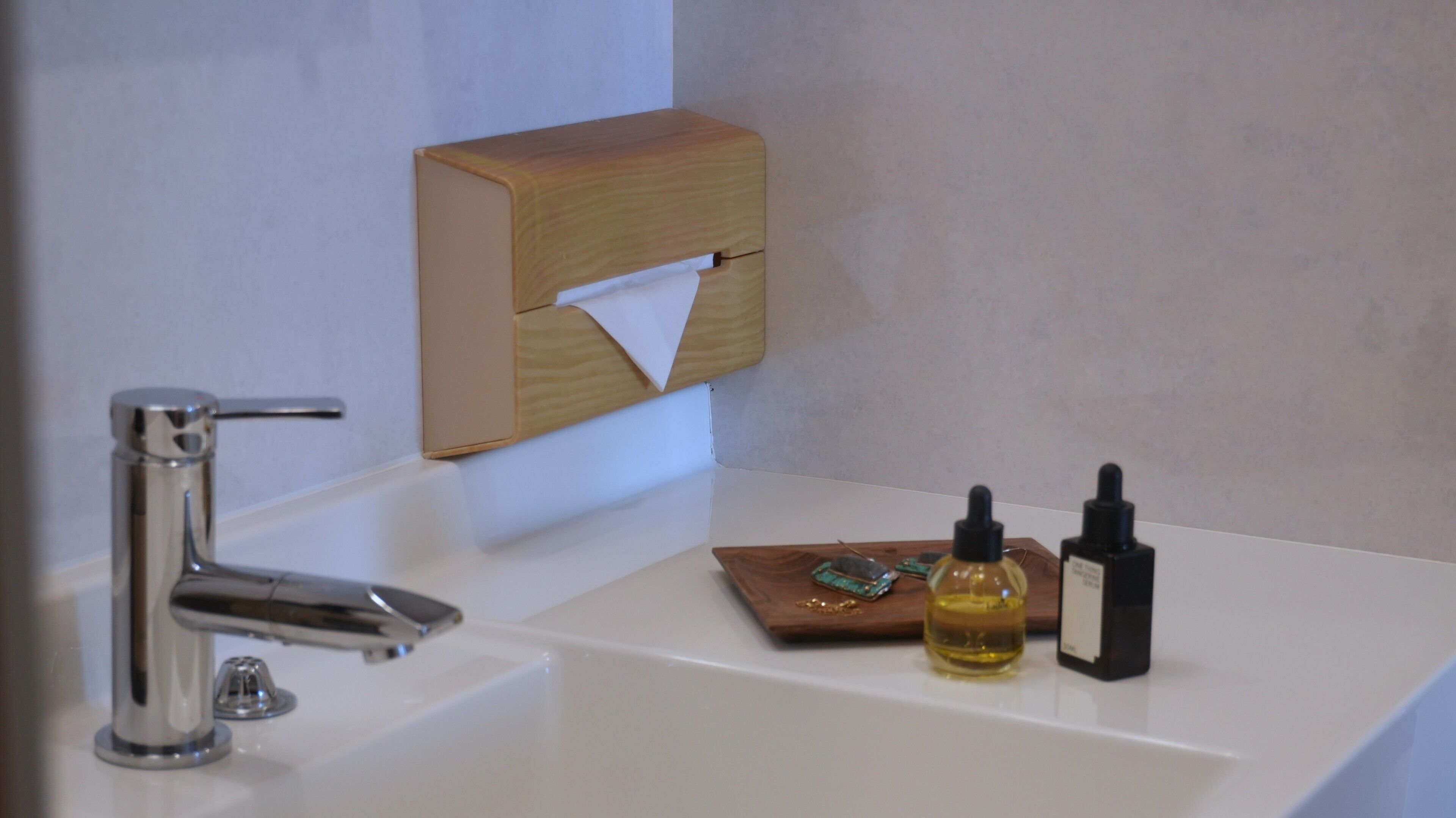 A bathroom sink with a chrome faucet, a tissue dispenser, and two bottles of liquid soap.