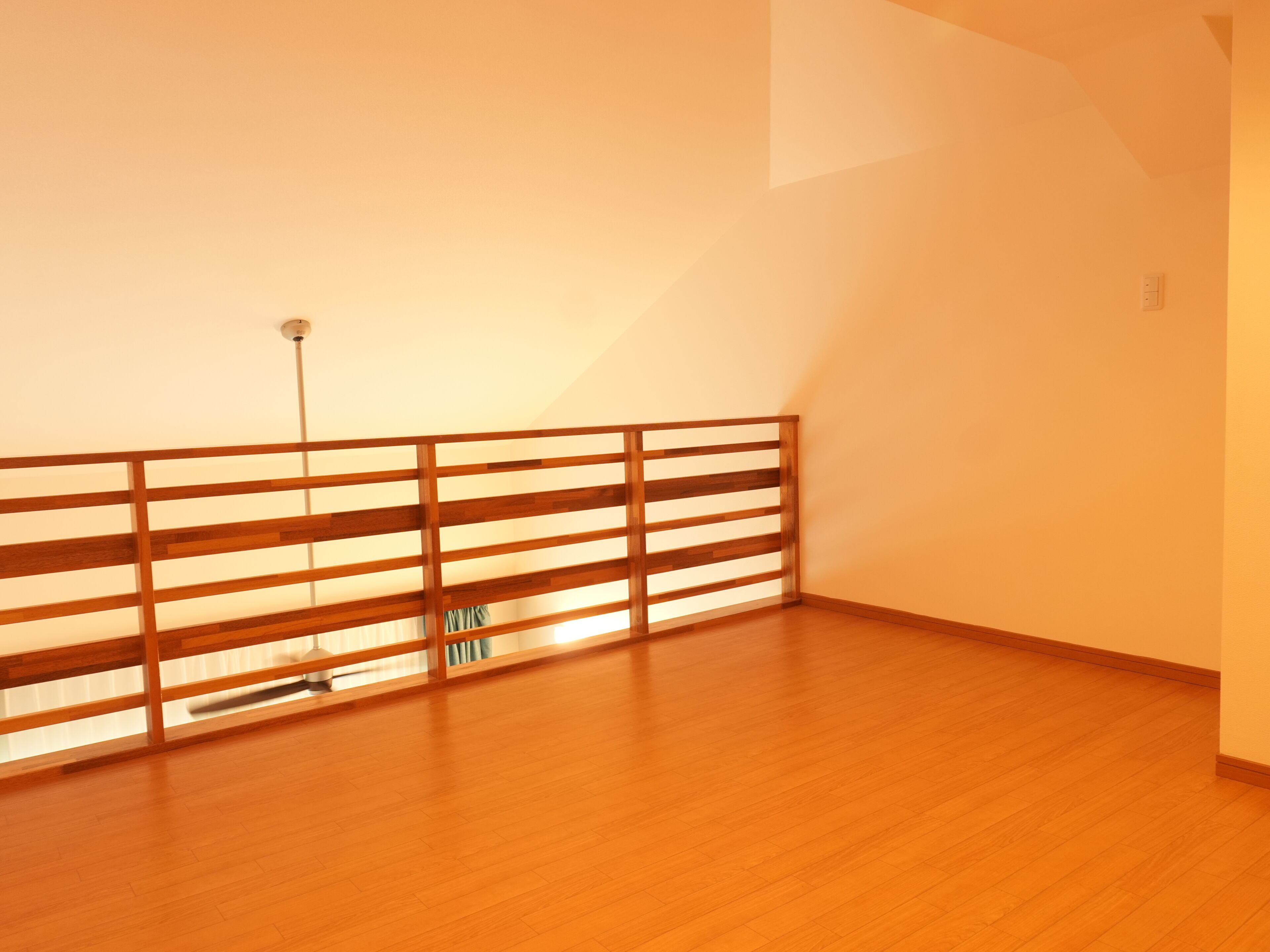Una habitación con suelo de madera, un panel divisor de madera con listones y un interruptor de luz en la pared.