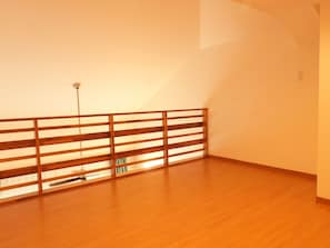 Una habitación con suelo de madera, un panel divisor de madera con listones y un interruptor de luz en la pared.