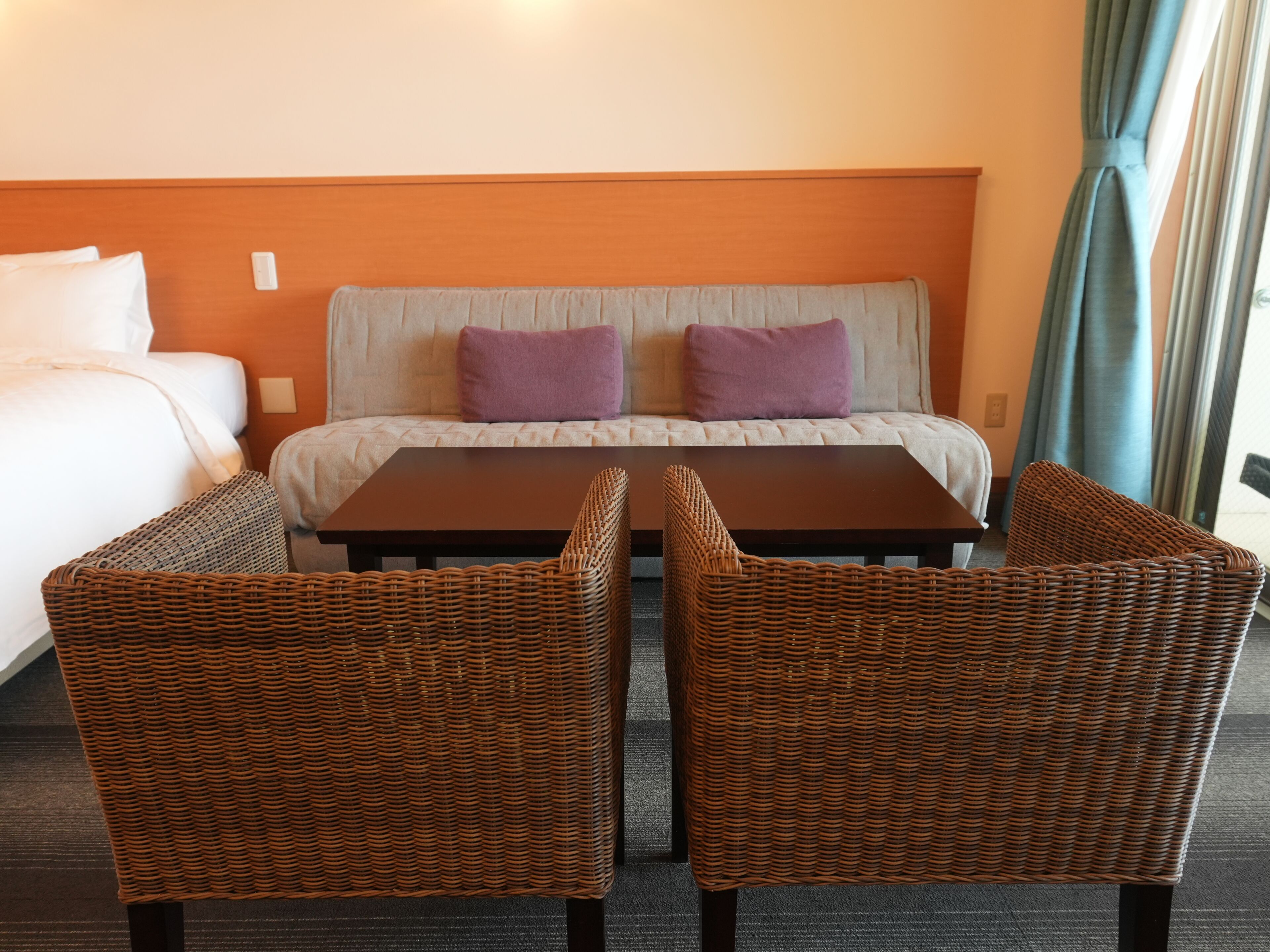 Une chambre d’hôtel comprenant un lit, deux chaises, une table et un canapé avec des coussins.