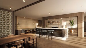A modern kitchen with a bar area, wooden flooring, and a seating arrangement with a long table and multiple chairs. - Hotel AMANO München Stachus (Munich)