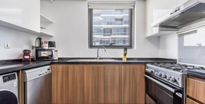 Eine kleine Küche mit Backofen, Mikrowelle, Kaffeemaschine und Spüle.