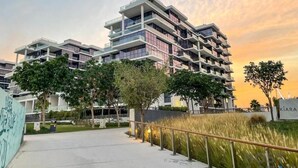 A multi-story residential building with balconies, a paved walkway, and greenery. - Orchid A Damac Hills - Host & Stay (Dubai)