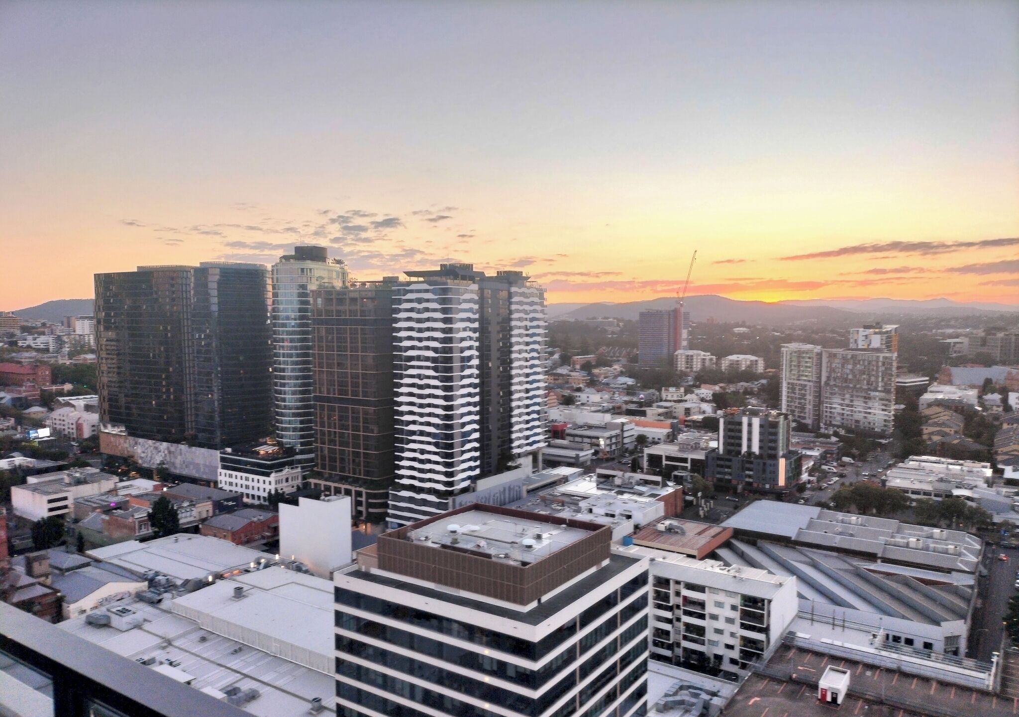 Une vue urbaine avec de hauts immeubles, un ciel dégagé et un coucher de soleil.