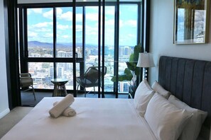 A hotel room with a large bed, a view of the city, a chair, and a table. - Luxe-valley 2BR 2bath Infinity Pool (Brisbane)