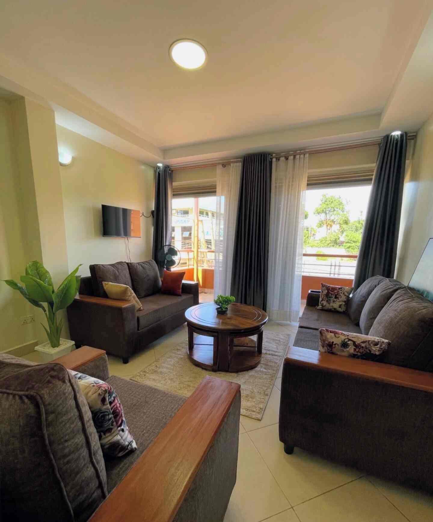 A living room with a sofa set, a coffee table, and a TV mounted on the wall.