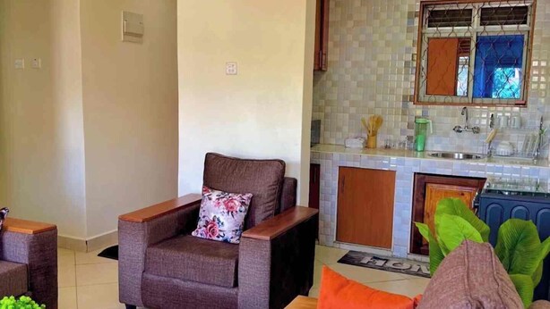 A living room with a sofa, armchairs, and a coffee table. - Izera Suites (Kampala)