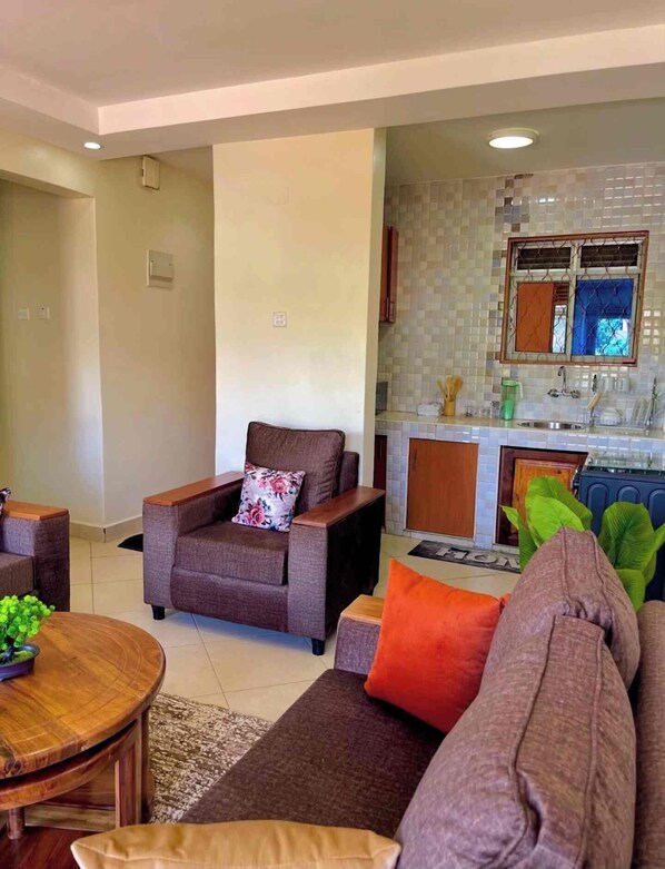 A living room with a sofa, armchairs, and a coffee table. - Izera Suites (Kampala)