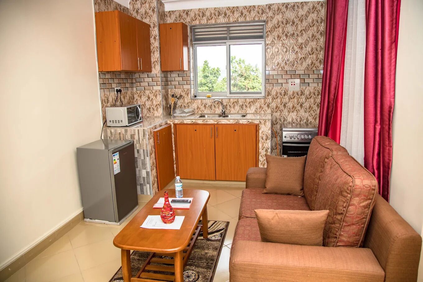 A compact living space with a kitchenette, a sofa, a dining table, and a patterned backsplash.