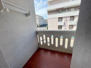 A balcony with a white railing and a view of neighboring buildings. - Practical studio with balcony by the beach (Porto Santa Margherita)